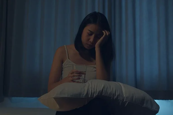 Image of a person taking melatonin supplements to aid sleep, in context with the blog post titled 'Is Melatonin Addictive: Exploring the Benefits, Side Effects, and Risks in 2023' by PatchMD - Vitamin Patches and Supplements.