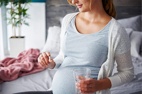 An illustrative image featured in the 'What to Avoid When Taking Glutathione' post by PatchMD - Vitamin Patches and Supplements, displaying a pregnant woman taking glutathione supplements