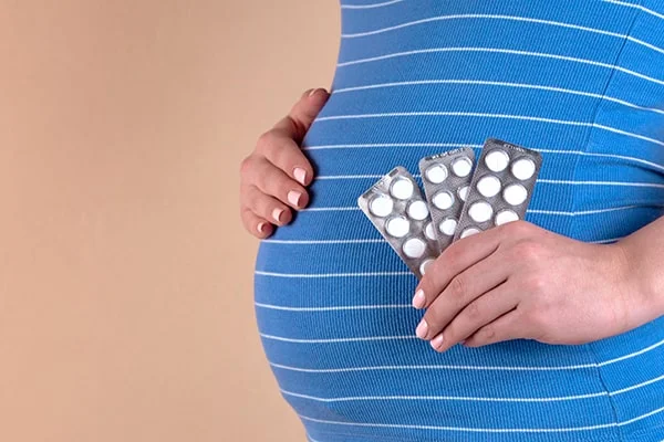 Image illustrating a pregnant woman holding a bottle of melatonin supplements, with a questioning expression, representing the topic of 'Can I Take Melatonin While Pregnant: Is It Safe?' in the blog post by PatchMD - Vitamin Patches and Supplements.