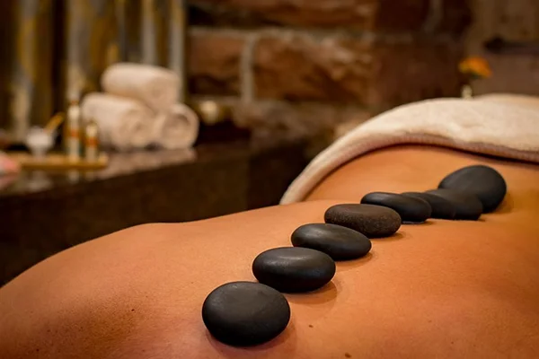 Visual element for the 'Managing Menopause and Joint Pain: A Practical Guide' post by PatchMD - Vitamin Patches and Supplements. Depicts soothing stones and a spa massage, symbolizing relaxation and well-being as part of managing joint pain during menopause 