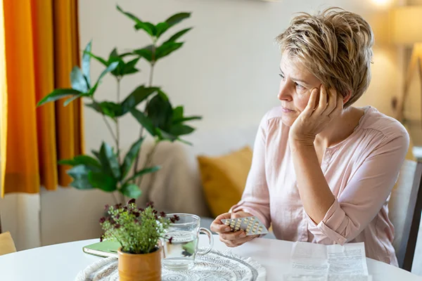 This image is featured in the 'Premenopause vs Perimenopause: Symptoms, Treatment, and More' post on PatchMD - Vitamin Patches and Supplements. It showcases a woman examining a chart illustrating tips for managing the menopause transition, labeled 'Premenopause vs. Perimenopause'.