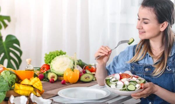 A person eating a vegetarian meal with a variety of vegetables and legumes