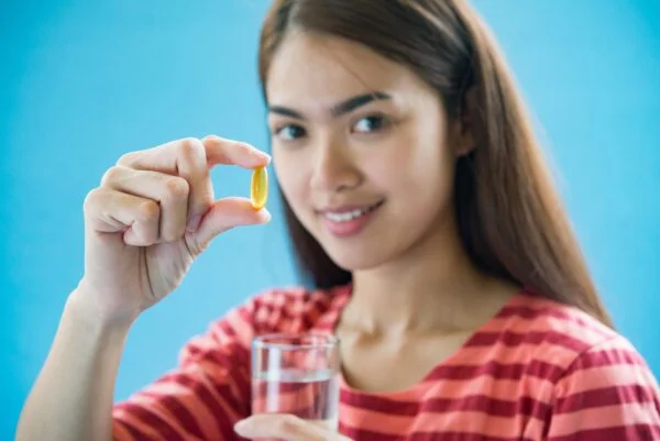 A person taking a vitamin B12 supplement to prevent and treat vitamin B12 deficiency