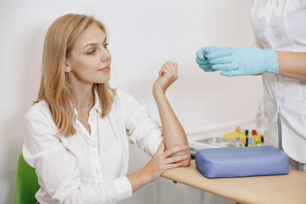 A person holding a test tube with a sample of blood for a magnesium test and a doctor looking at the results