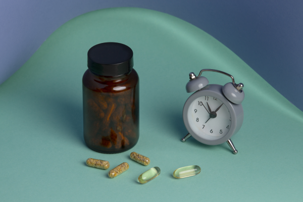 A picture of a bottle of magnesium supplements with a clock showing the time when to take magnesium for sleep